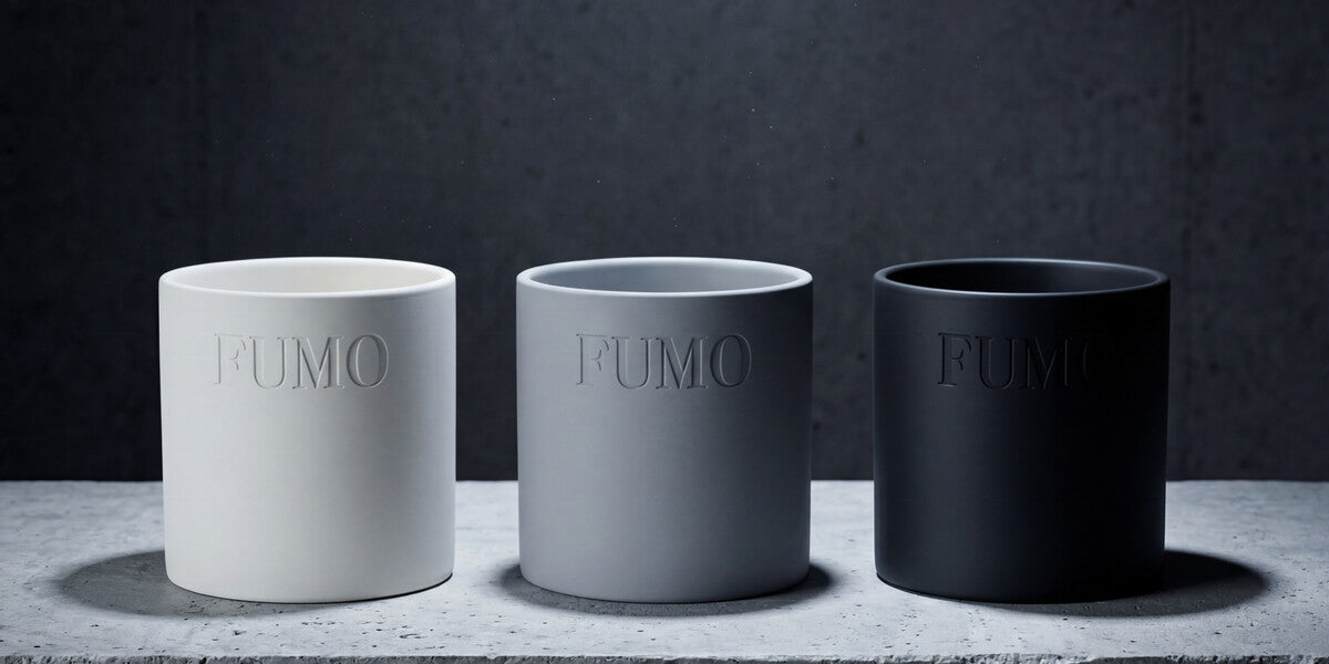 FUMO candle vessels in white, grey, and black on a display shelf